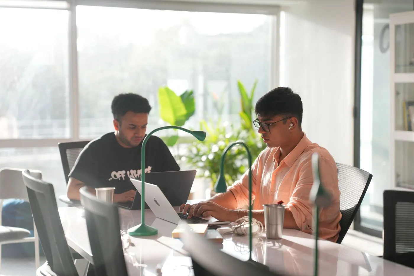 Two learners building with AI at their laptops