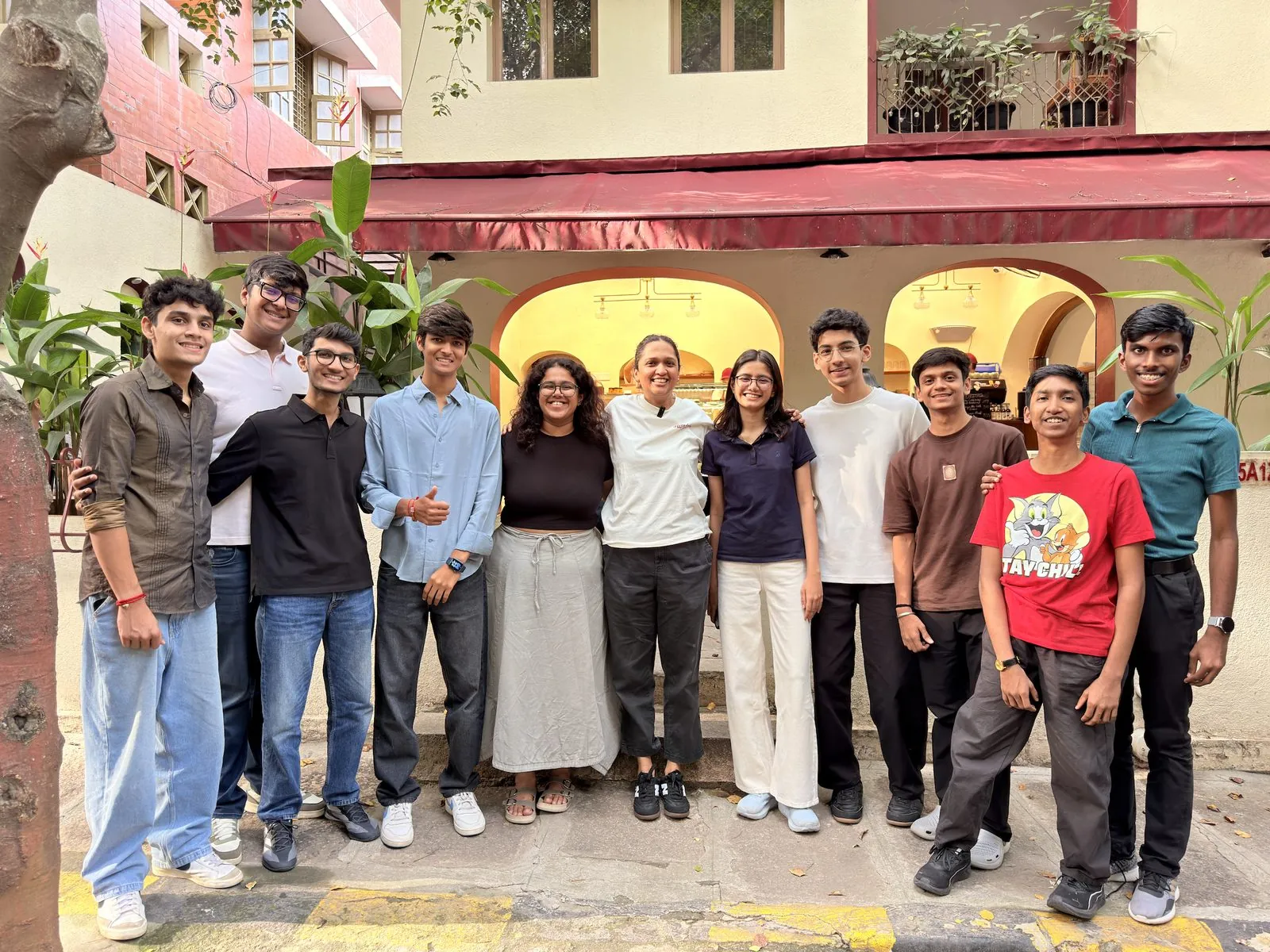 Mesa students and a guest standing together in front of a cafe