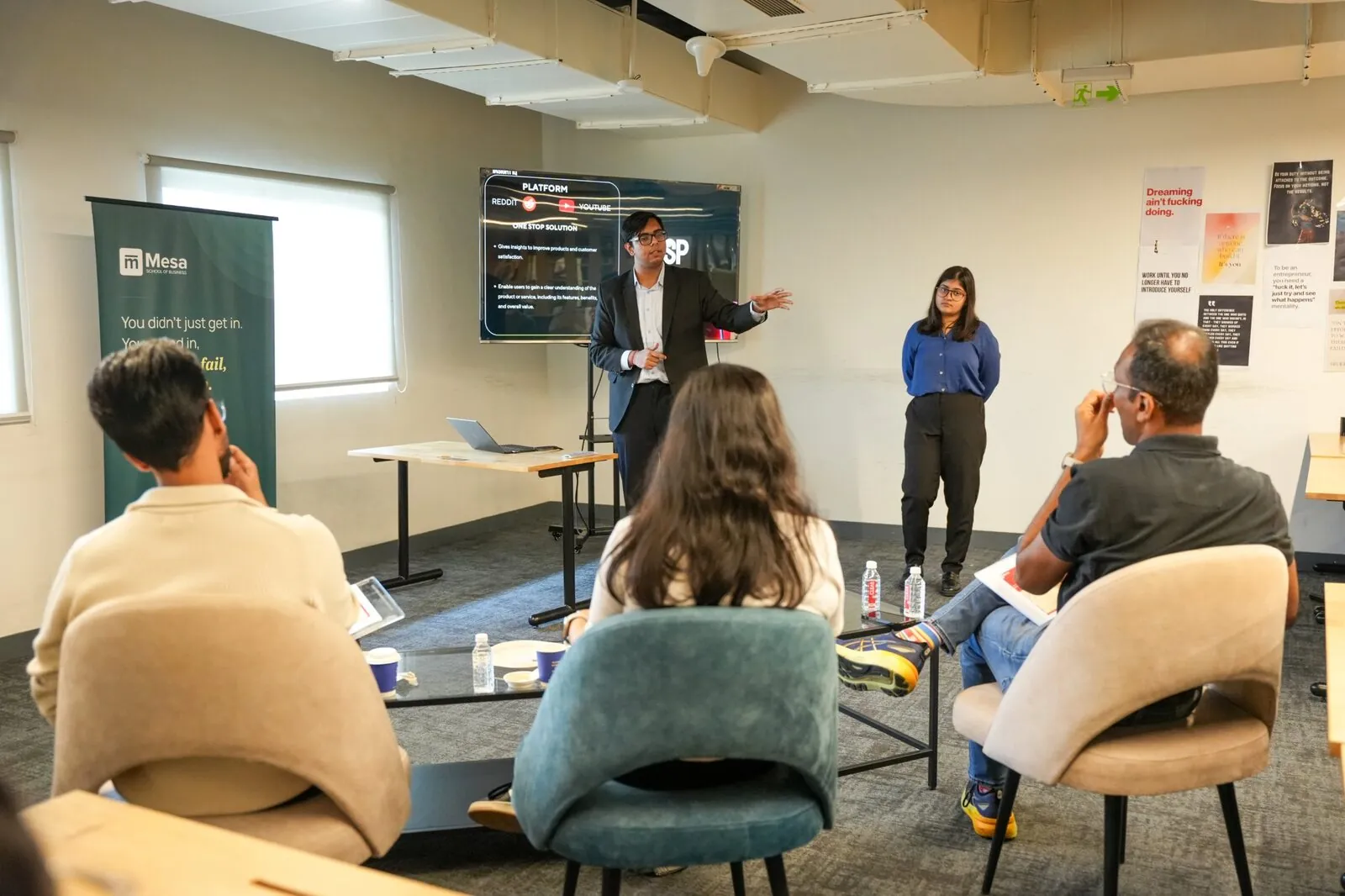 Two students pitching their product to a panel at Mesa