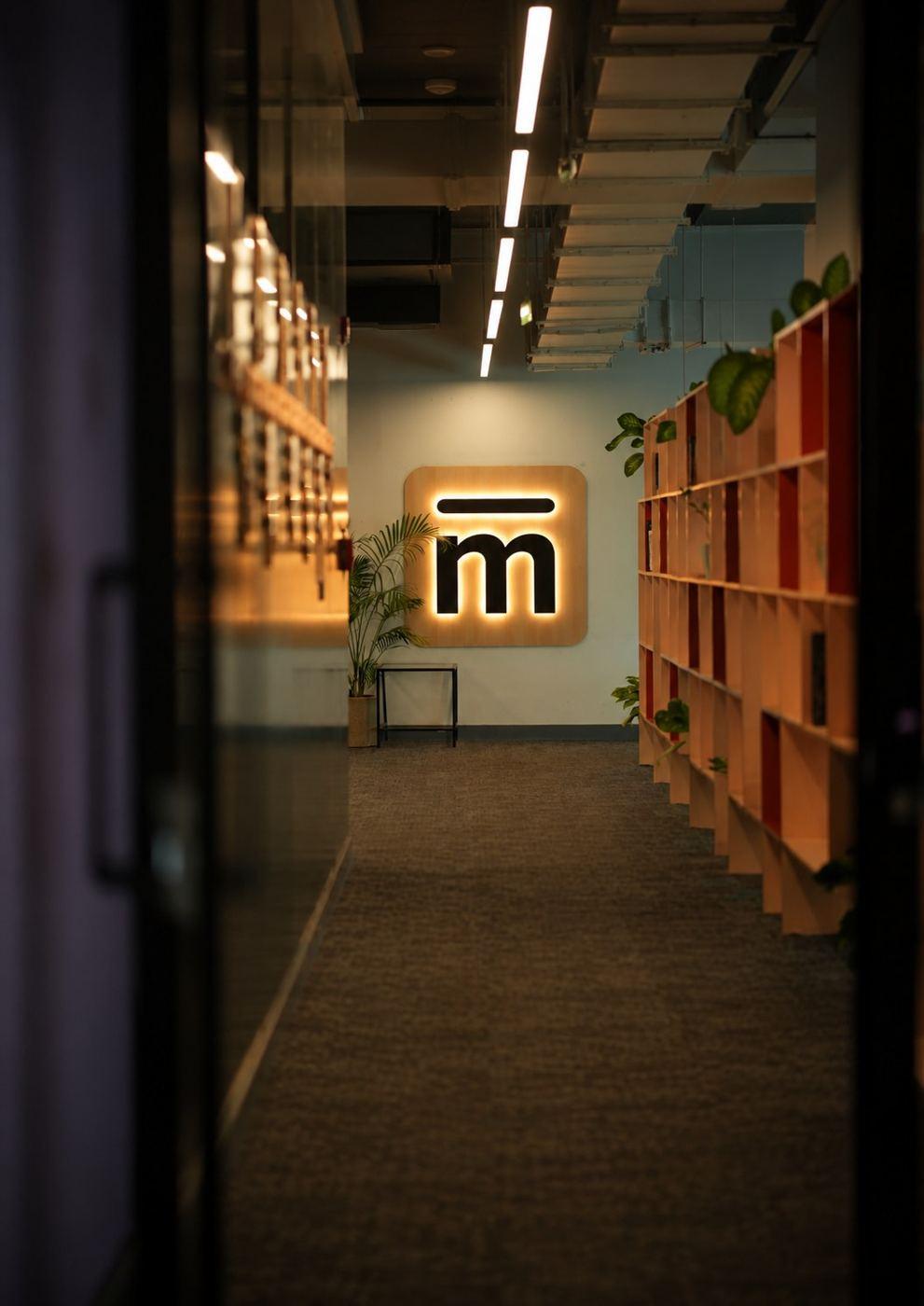 A corridor at Mesa’s campus leading to the lit Mesa logo