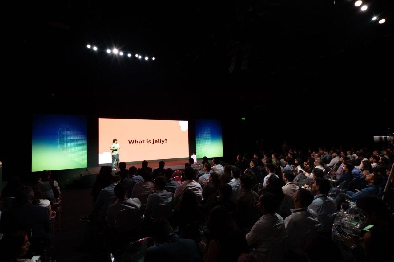 A founder presenting on a large stage to a packed audience
