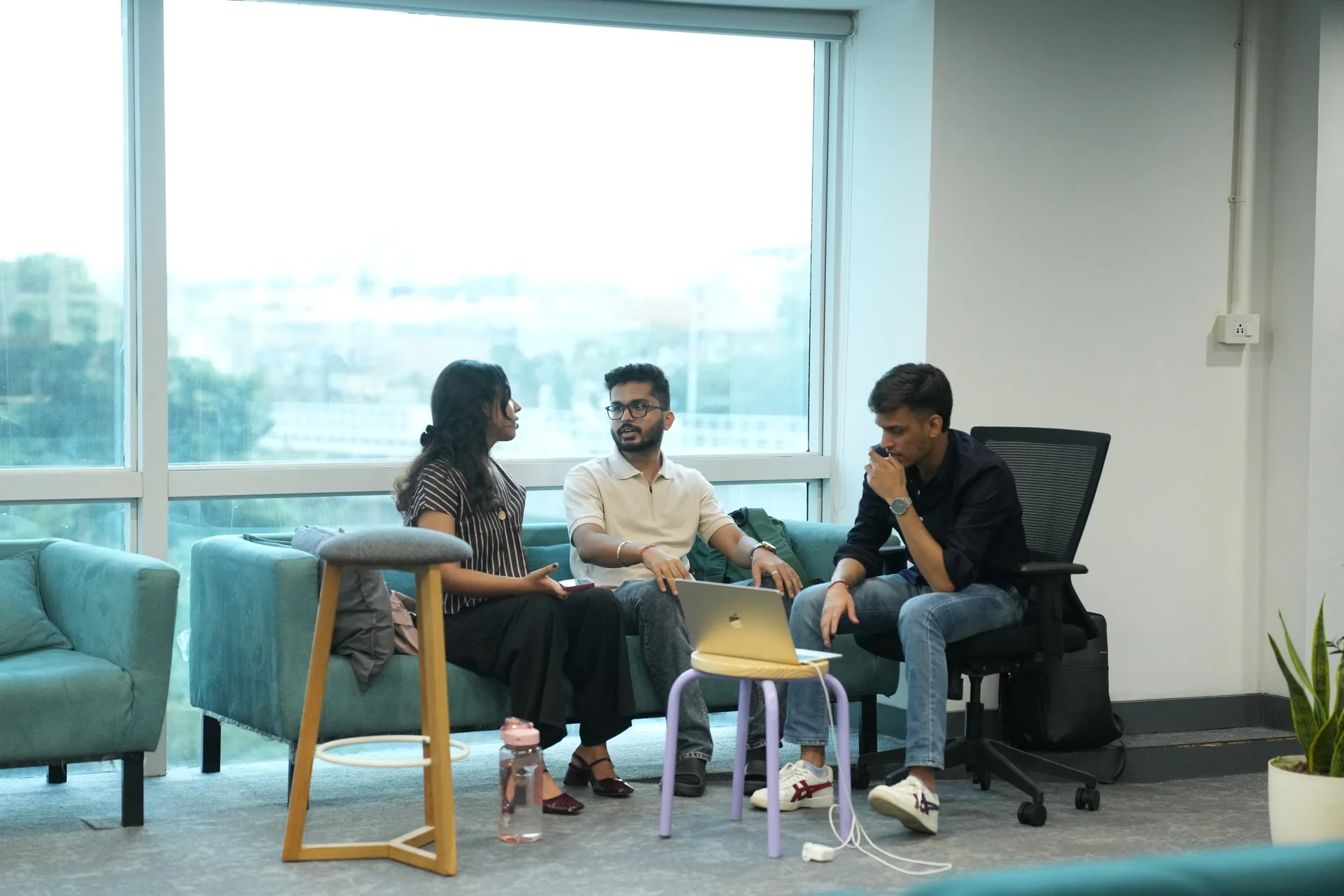 Three students chatting on the sofas by the window