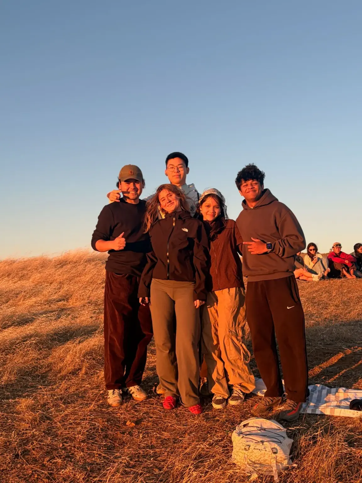 Mesa School undergraduate students on a grassy hilltop at sunset